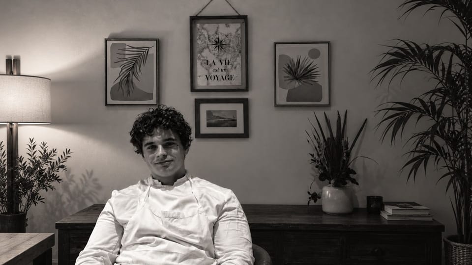 Ugo en tenue de chef, assis, en noir et blanc