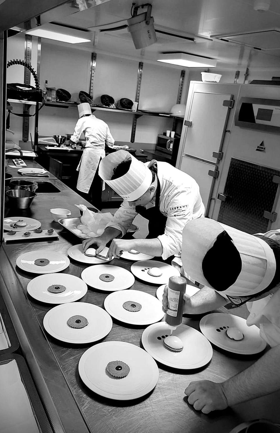Ugo et la brigade au dressage d'une série d'assiettes, en noir et blanc